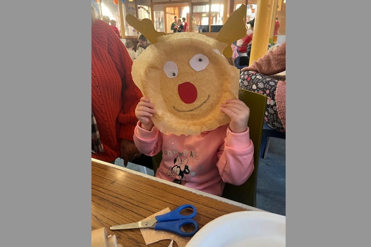 A youngster with their paper plate face made at Crediton Congregational Church Toddler Group.
