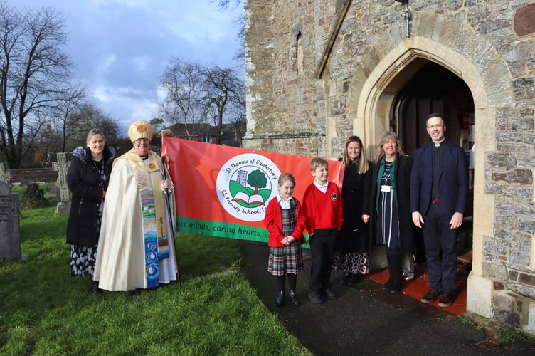 9 January 2026 Lapford school name change Bishop of Crediton Moira Astin, left, Rev Jeremy Putnam, right, Head of School Jessica Wright, third from right, and others with banner featuring new logo (Will Goddard, Crediton Courier)