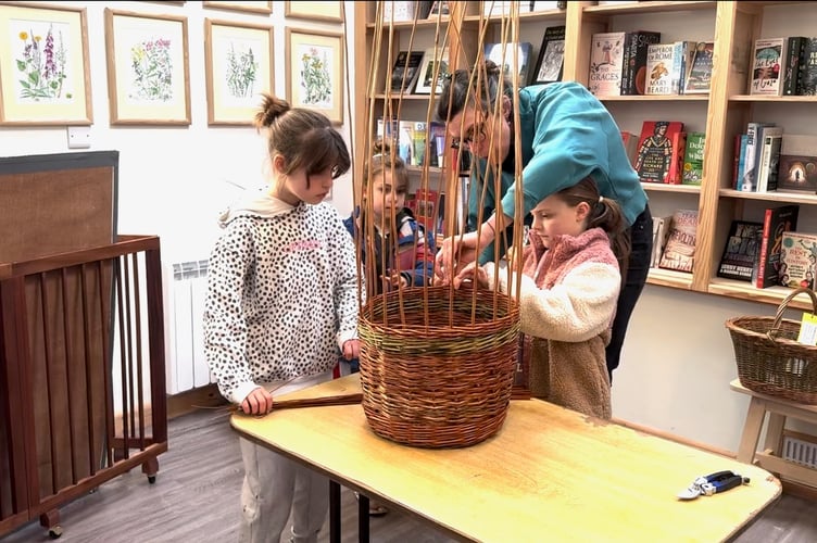 Young people being shown how to help make the Crediton Community Basket.
