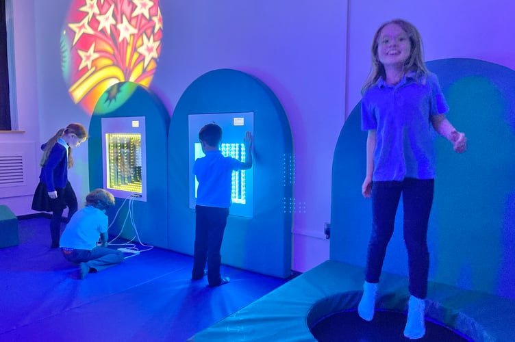 Children enjoying the trampoline and light displays inside the new room