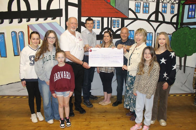 Frederick Caygill, from Dementia UK, fourth left, receiving £350 from Tedburn Amateur Dramatic Society officers and some of the younger members.  AQ 1165
