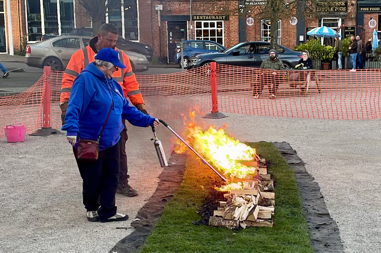 President Ann Whitehouse lighting logs doused in kerosene