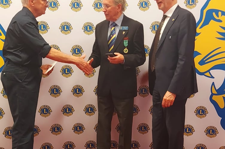 Lion Eric Parkes, centre, receiving an award for his 20 years’ service administering the Peace Poster competition locally and in the district.

