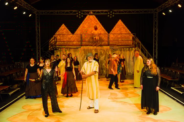 Jacob, played by Mike Canning, with the narrators Vicky Lancelets and Dani Gwyn and other cast members on stage.
