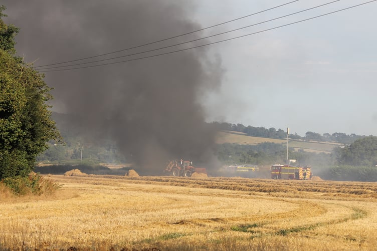 Thick black smoke rose from the tractor and bailer fire. AQ 1585