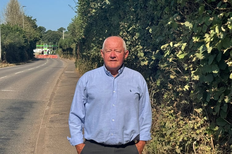 County Councillor Jim Cairney in front of the trimmed hedge and clear footpath along the A377 between the Tesco roundabout and Asda Express Petrol Station. AQ 5134