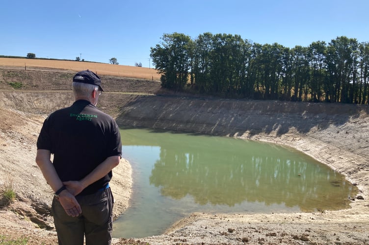 An Environment Agency officer at a farming reservoir experiencing very low water levels earlier this month.