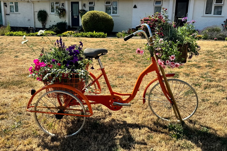 A tricycle decorated with flowers on Newton St Cyres village green to highlight sustainable travel and the Boniface Trail. AQ 5001