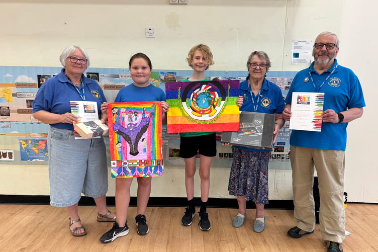 Crediton Lions Ann Whitehouse, left and John Whitehouse, right, with the Landscore School peace poster winner Elliott and runner-up Esme. AQ 6235