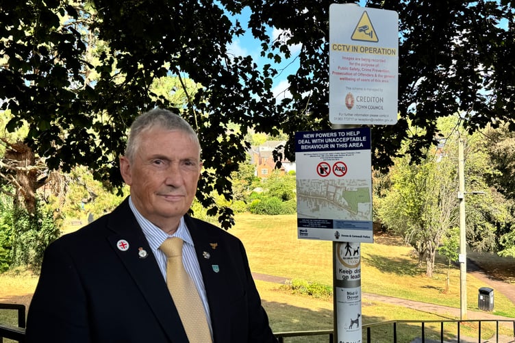 Councillor Guy Cochran, Cabinet member for Quality of Life, Equalities and Public Health and Leader of Mid Devon District Council, beside one of the signs at Newcombes Meadow. AQ 9289
