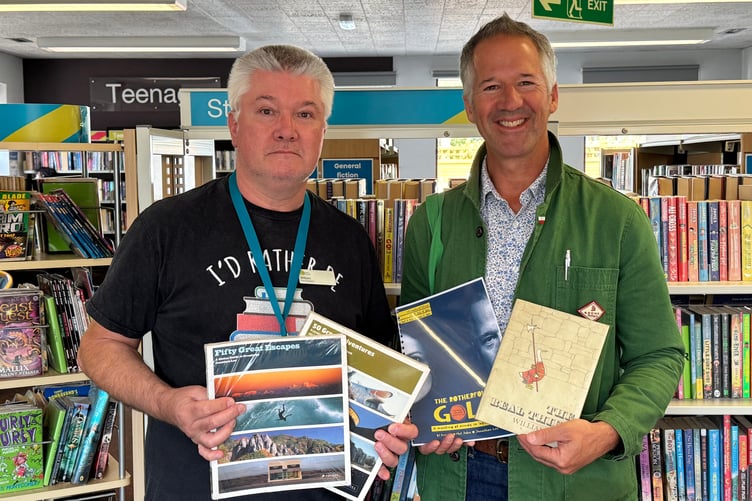 William Mearns, Crediton Library First Assistant, left, receives the donated books with Jonathan Lee holding the script and book he borrowed 50 years ago. AQ 9526