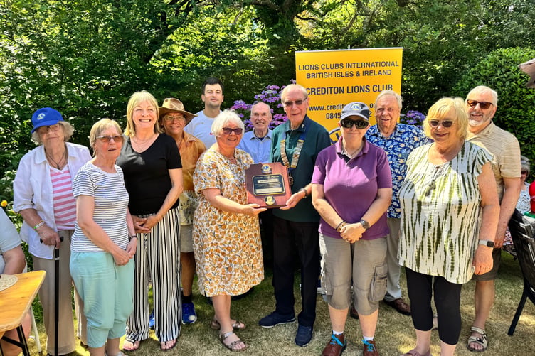 Eric Parkes, Crediton Lions President presents outgoing president Ann Whitehouse with the Melvin Jones Fellowship, surrounded by club members. AQ 4817