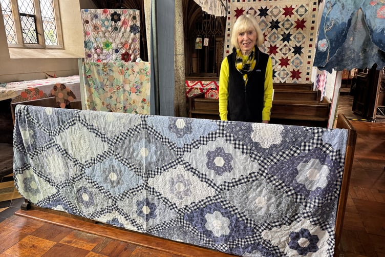 Margaret Morris with the quilt she created, sections she made on flights to Holland when she worked overseas. AQ 0108